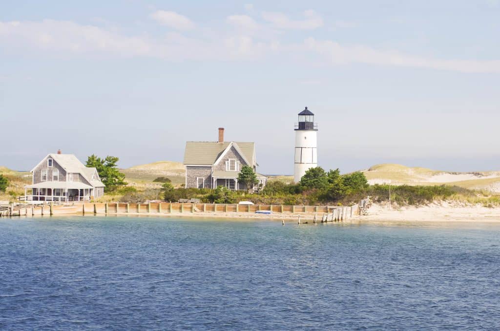 A body of water with a lighthouse and houses in the distance in New England