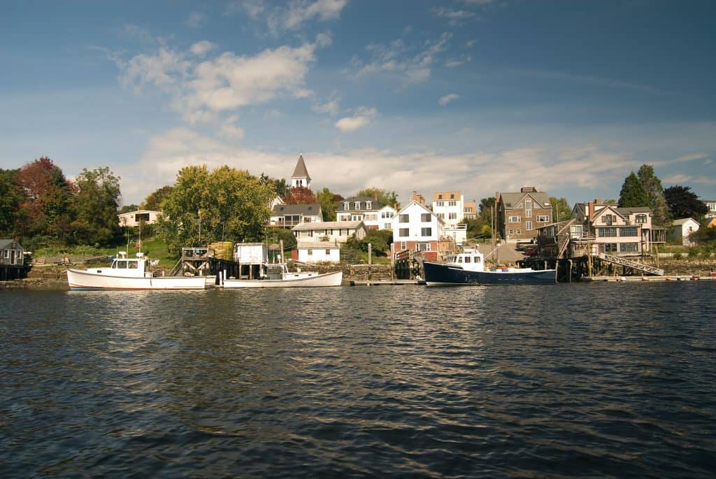 A body of water with boats and buildings in the distance in New England.