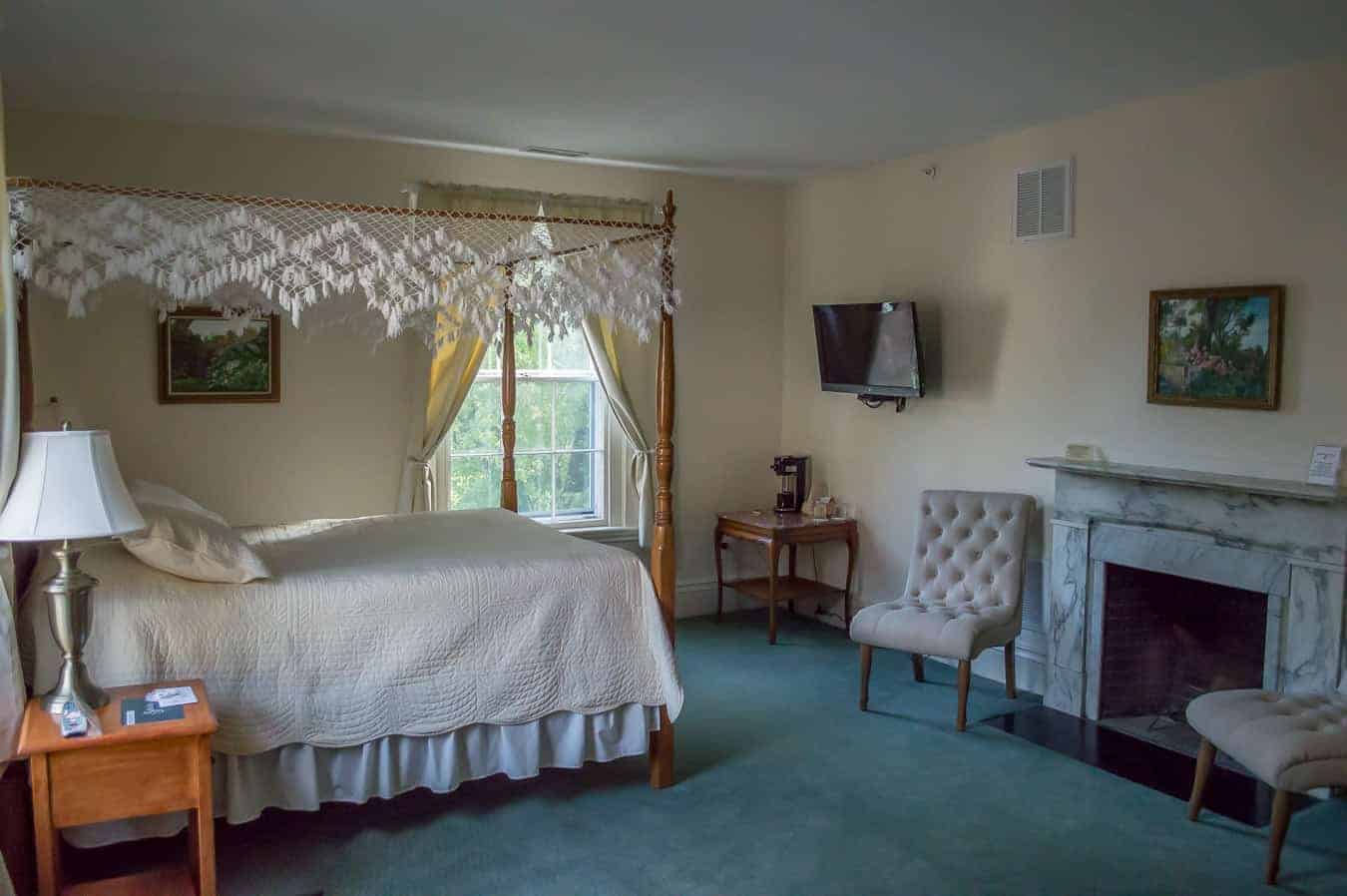 Old fashioned canopy bed with white covers and lace canopy