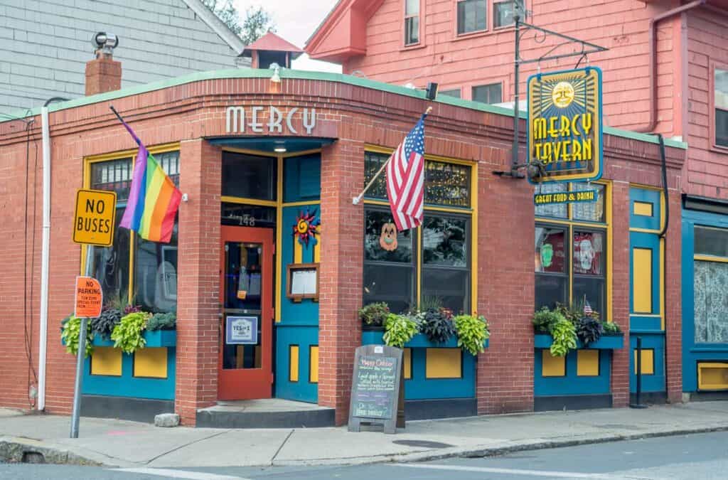 Pink corner building with American flag and a sign saying "Mercy Tavern"