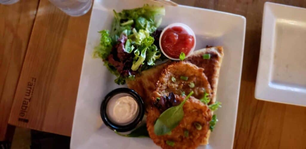 Food on a plate, featuring salad, dips, and a quesadilla.