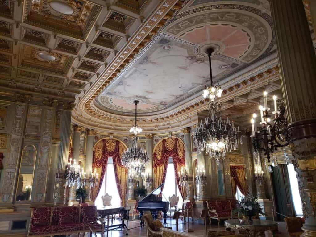 A formal room in a mansion with a decorative ceiling and a chandelier