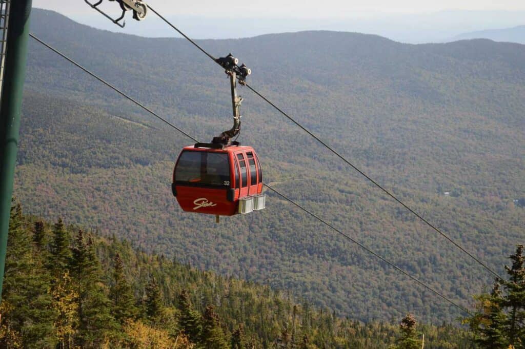 A red cable car with mountains in the background.