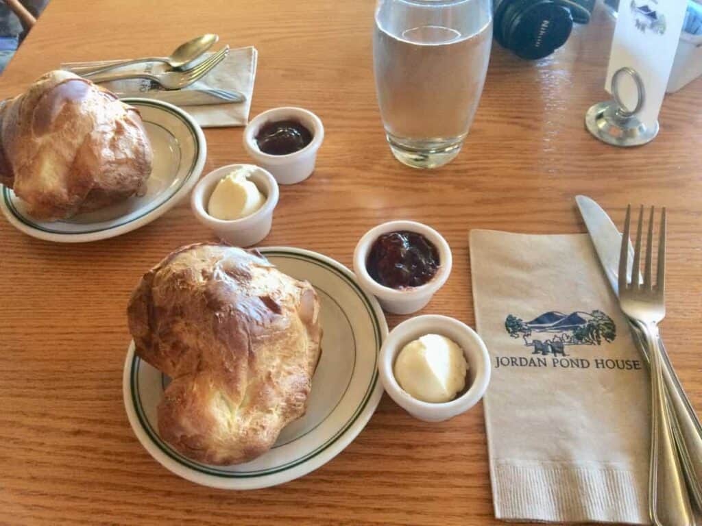 A plate of food on a restaurant table - two fluffy popovers with butter and jam