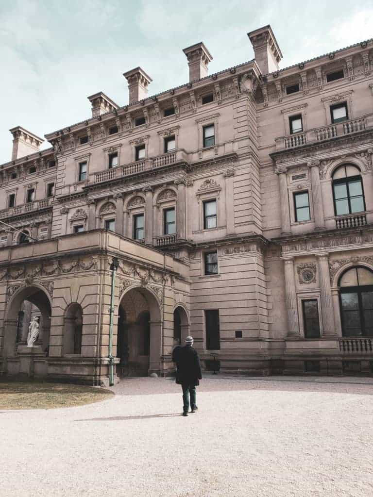 A man walks towards a towering Newport Rhode Island Gilded Age mansion