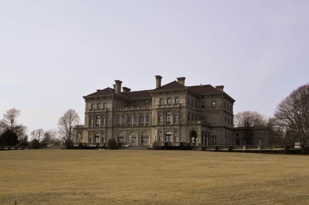 A grey castle in the distance with brown grass in the foreground