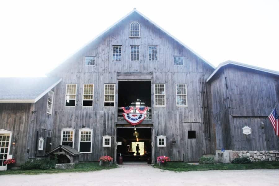 Historic grey barn with the doors open, beckoning people inside, under a sunny bright sky in Litchfield Hills Connecticut.