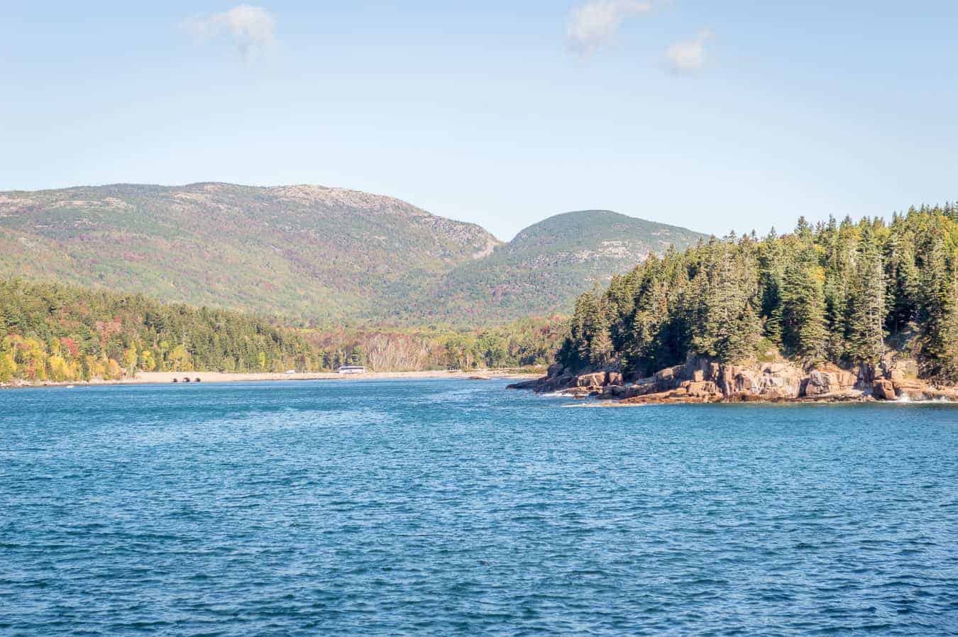 Blue lake with waves surrounded by mountains and forests under a blue cloudy sky is one of the top Acadia National Park things to do
