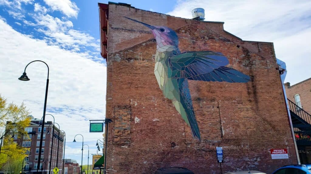 A large hummingbird painted on a red brick building