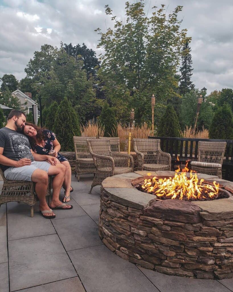 Man and woman hugging and sitting in front of an outdoor fire pit