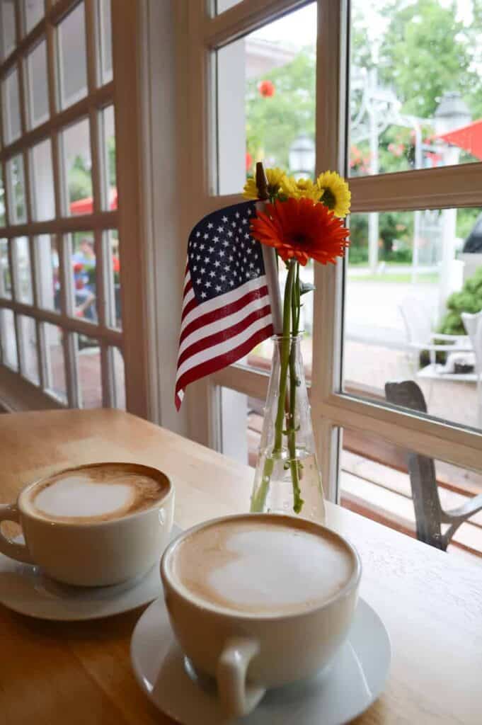 Two cups of cappacino with a vase with flowers and an American flag in Woodstock Vermont