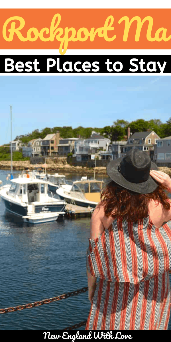 Woman holding a black hat on her head while looking at boats floating on the blue water.