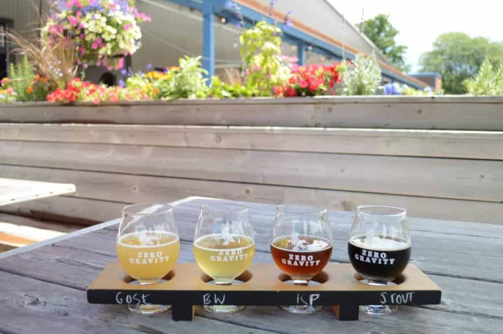 Four glasses of beer in a flight at a Burlington brewery sit on a table on an outdoor patio.