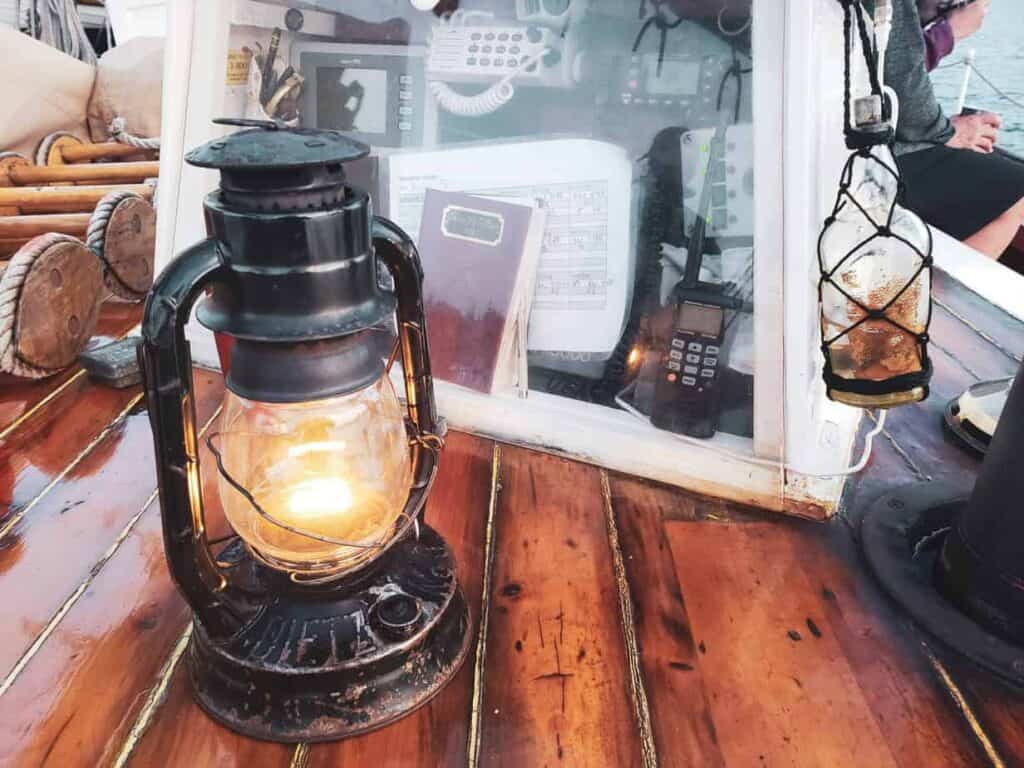 A historic lantern sits on wood surrounded by other small artifacts, like journals and phones.