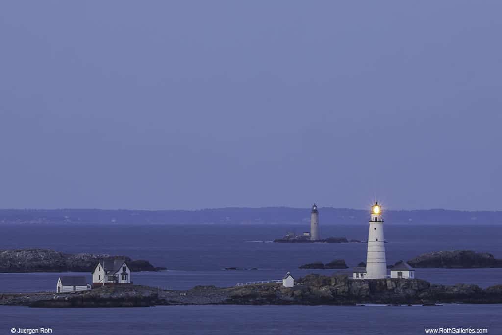 Two lighthouses on rocky islands surrounded by water at night.