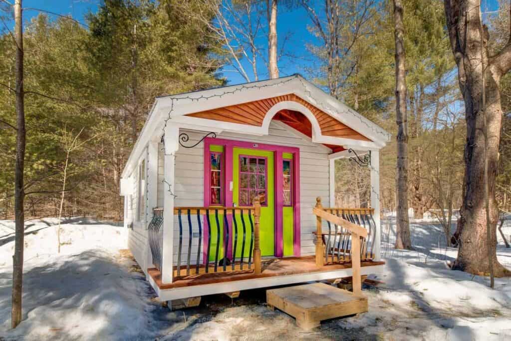 Small colorful Airbnb in New England with porch in the snowy woods 