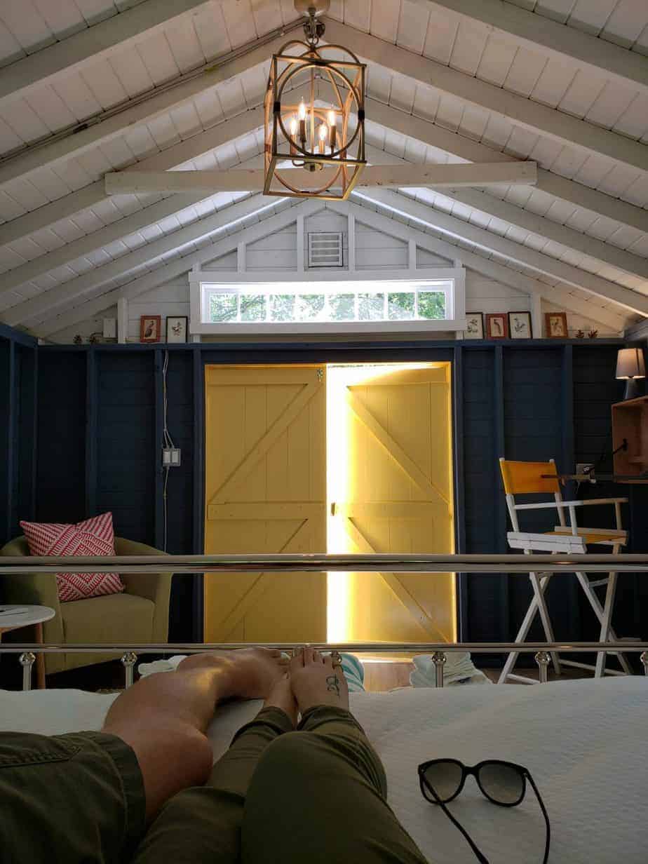 View of yellow doors opening in a wooden cabin glamping site, from bed.