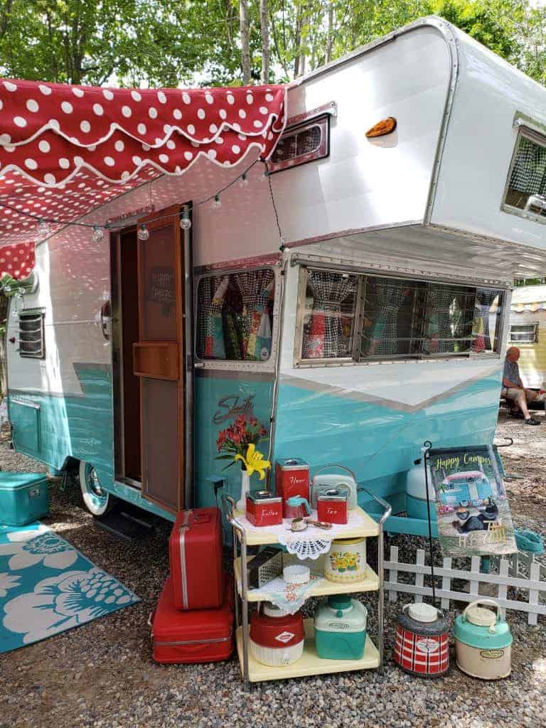 Blue and white RV with a red polka dot awning.