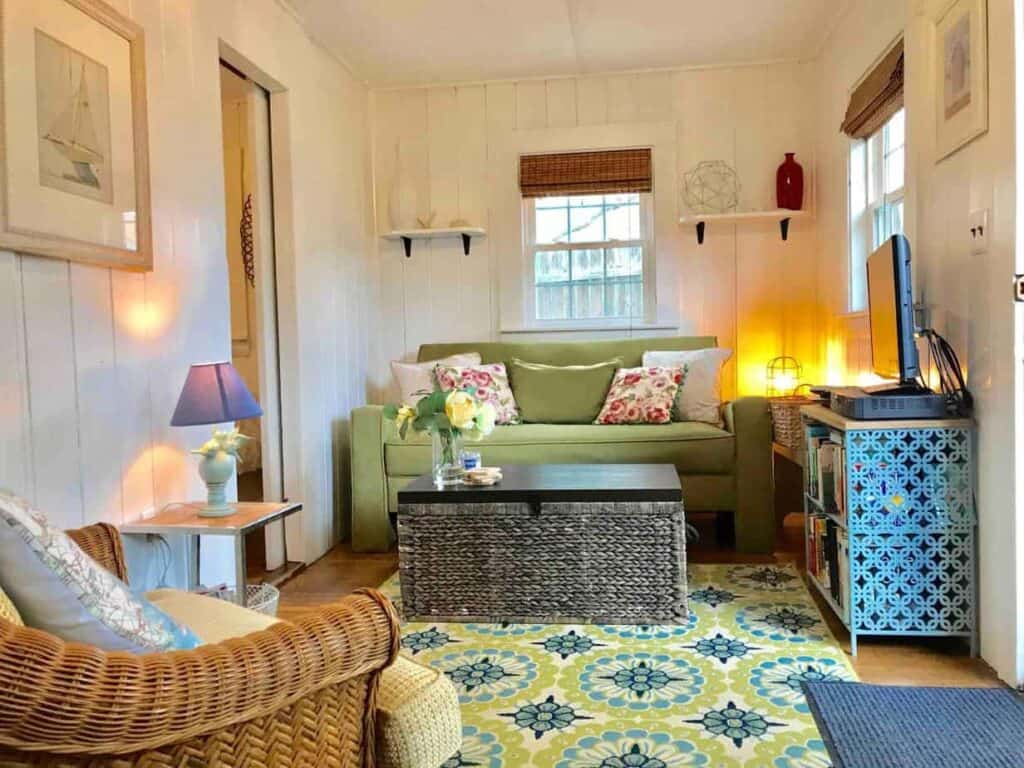 A cozy sitting room with a green couch and wicker chair in a Cape Cod VRBO