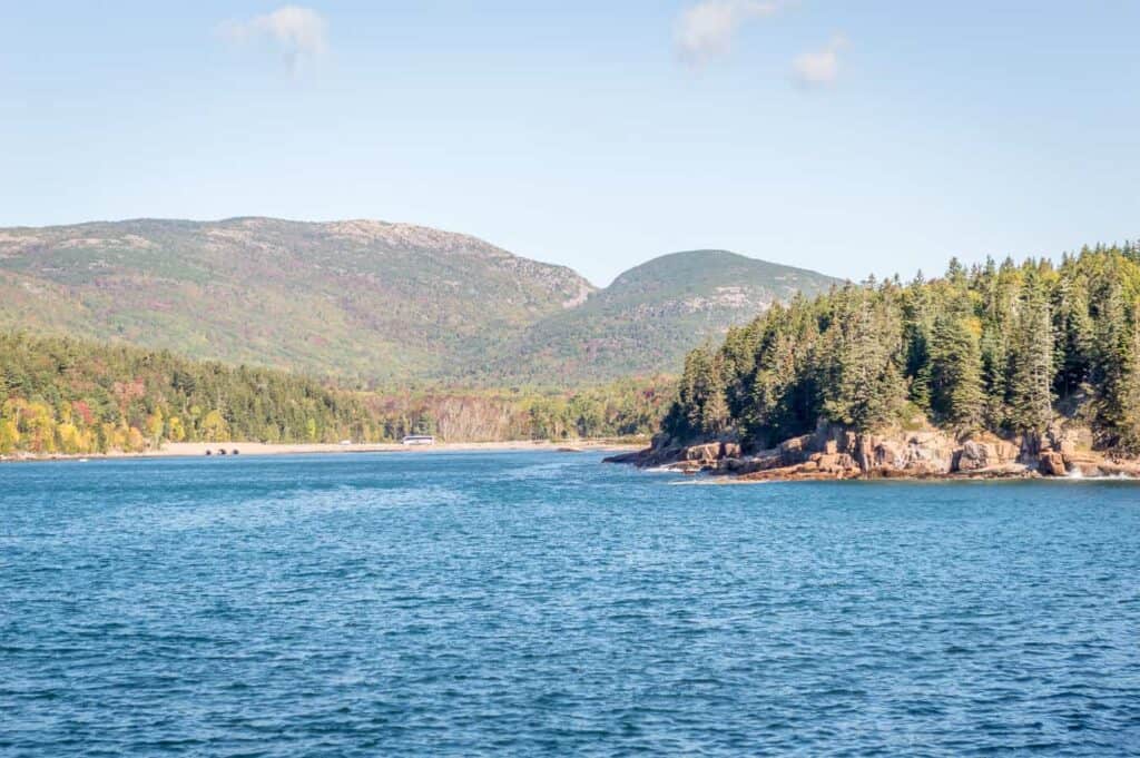 A large body of water with a mountain in the background under a blue sky.