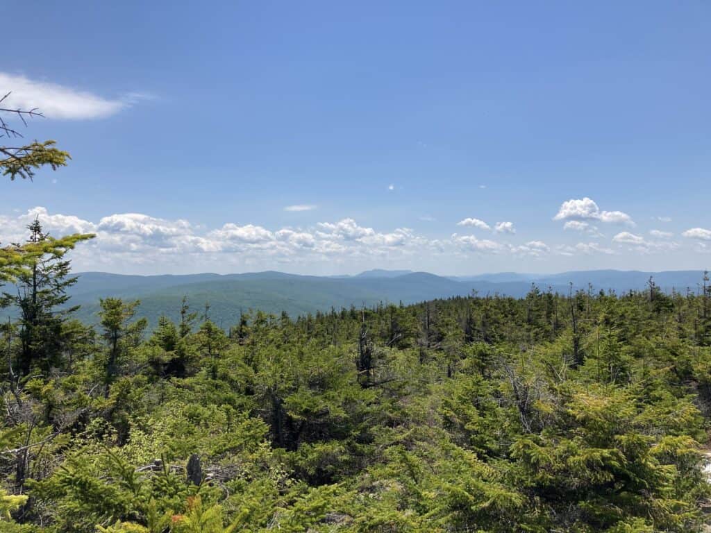 A green mountain with distant mountain ranges in the background