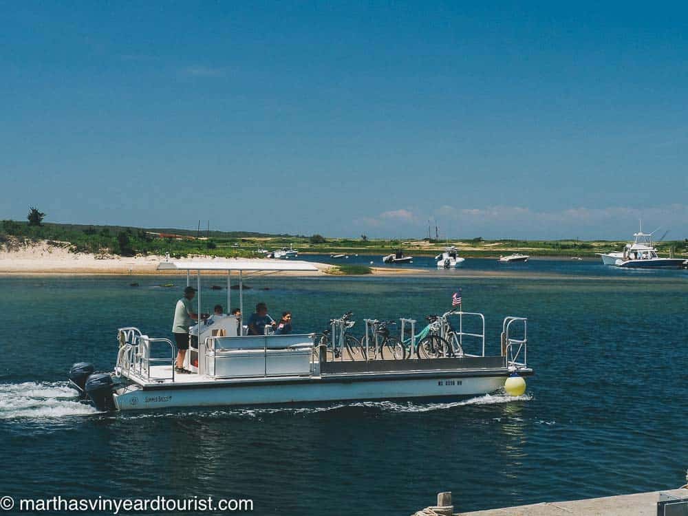 A ferry boat on blue water with a beach in the distance