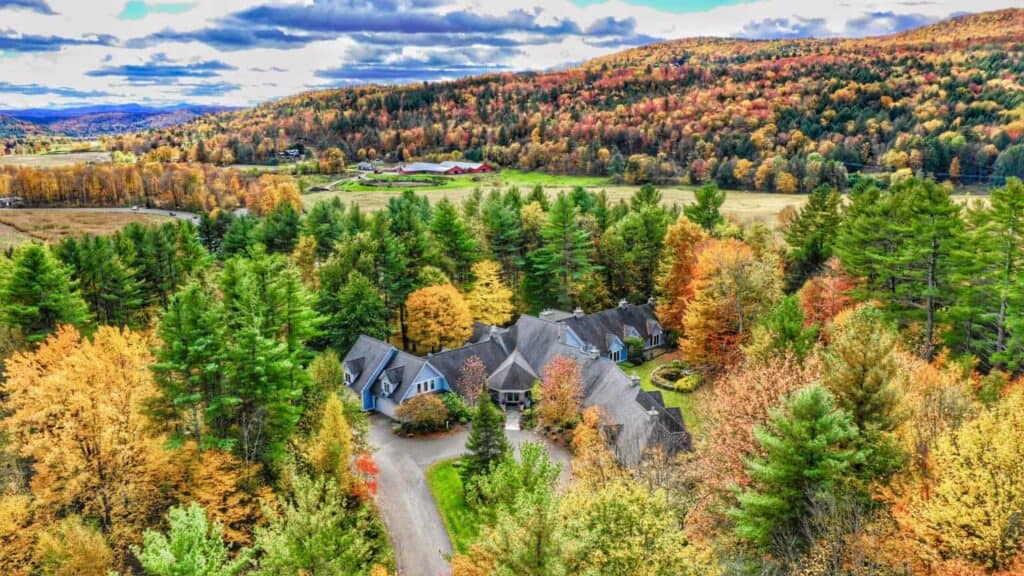 Aerial view of a New England romantic destination surrounded by forests with fall foliage.