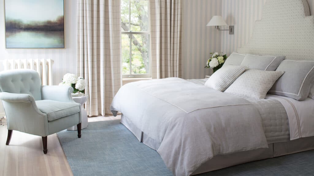 Bedroom in a hotel with neutral colored bedding and a light blue carpet during a Massachusetts romantic getaway