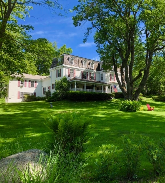 A house with bushes in front of a lush green field