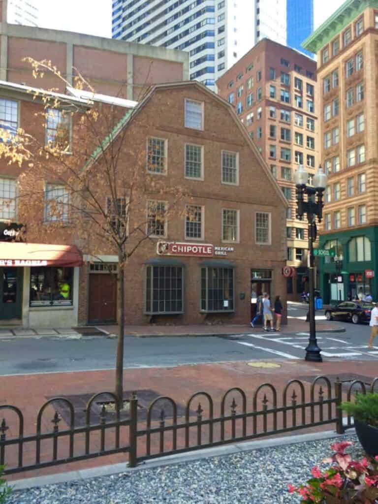 Brick building with a red sign that says \"Chipotle\" on the street downtown.