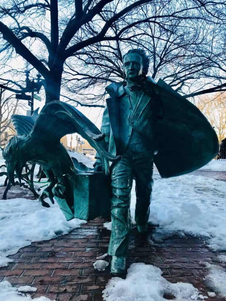 Green statue of a man holding a brief case and a bird.