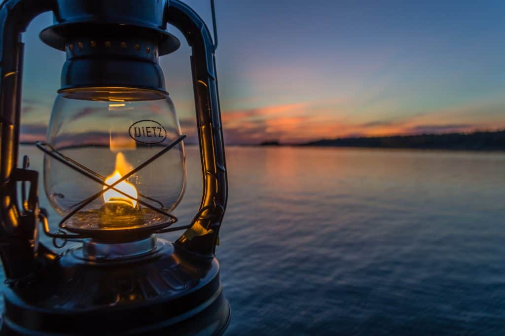 A closeup of a lantern on a body of water at sunset