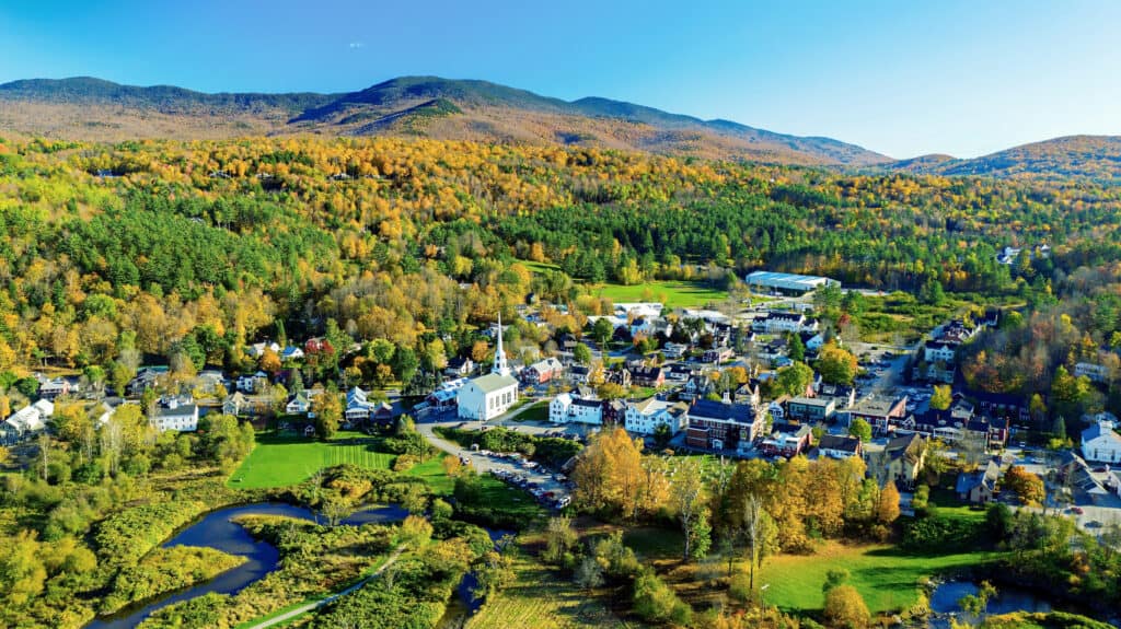 Aerial view of a New England vacation destination surrounded by mountains with fall foliage.