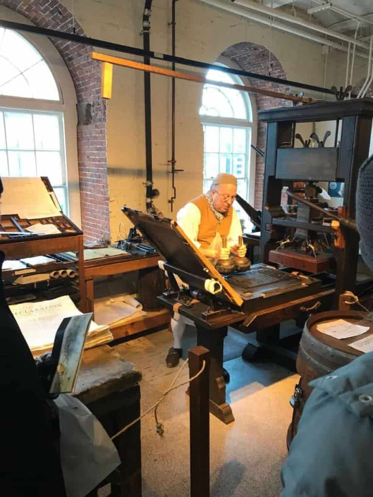 Statue of a man working on a printing press.