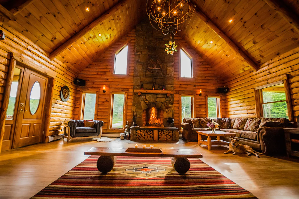 Interior of a very large chalet with a a stone fireplace in the center in Vermont