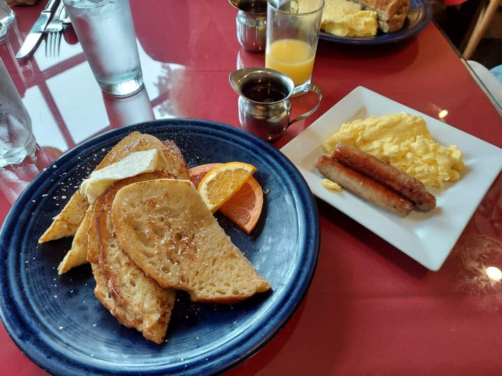 Plate with sandwich and fruit wedges on a blue plate with a sandwich next to it on a white plate