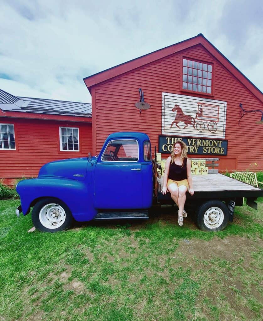 Girl standing in front of a blue truck with a red building behind her