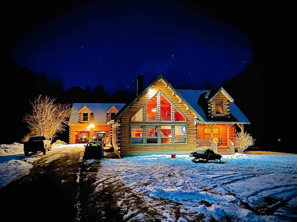 A chalet in the evening lit up with a snow covered ground in Vermont
