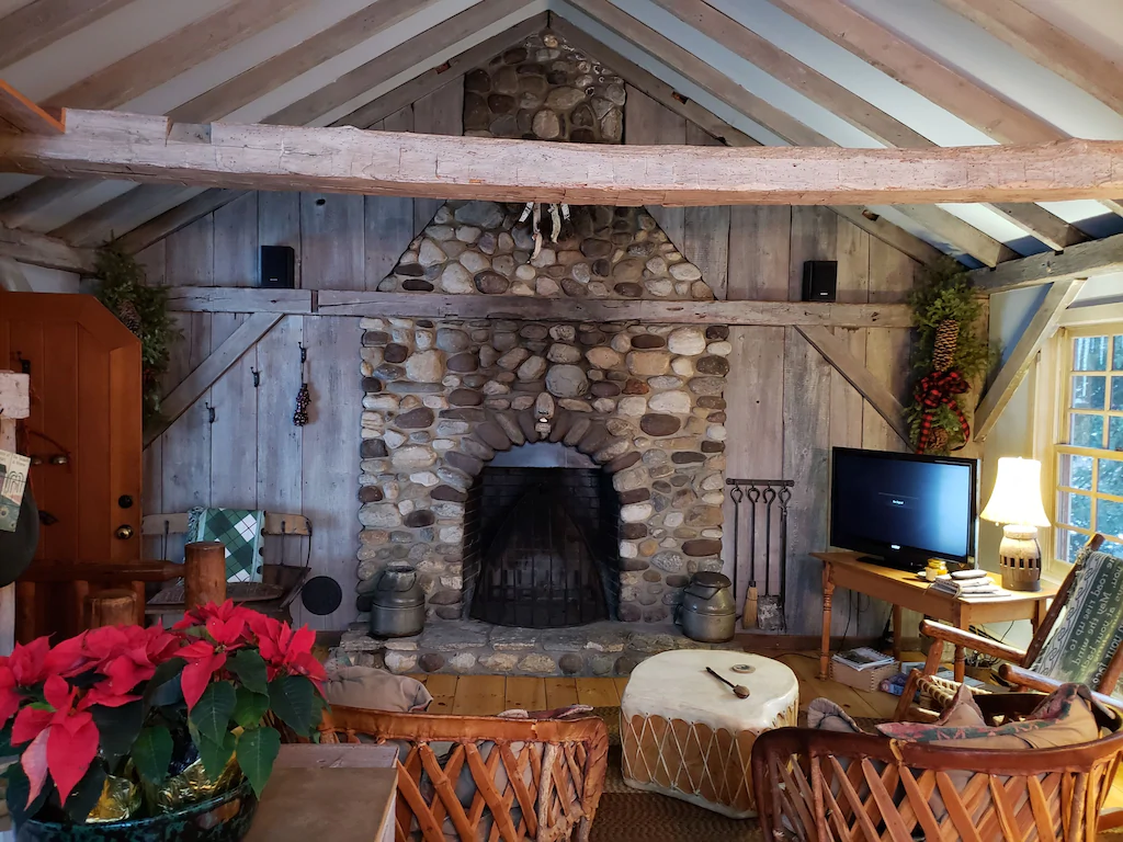 Living area of a chalet with a large stone fireplace in Vermont