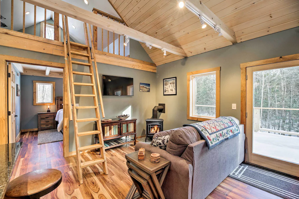 A living room with a sofa and a ladder leading up to a loft in Vermont