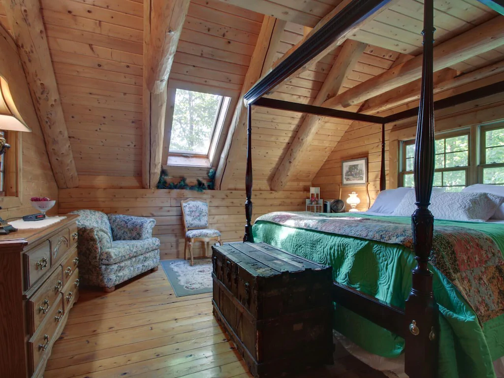 A four poster bed and sitting chair in a Cape Cod style room