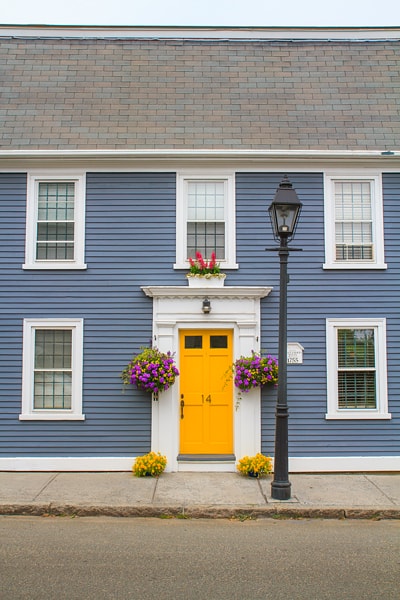 A yellow door with white trim around it on a blue house