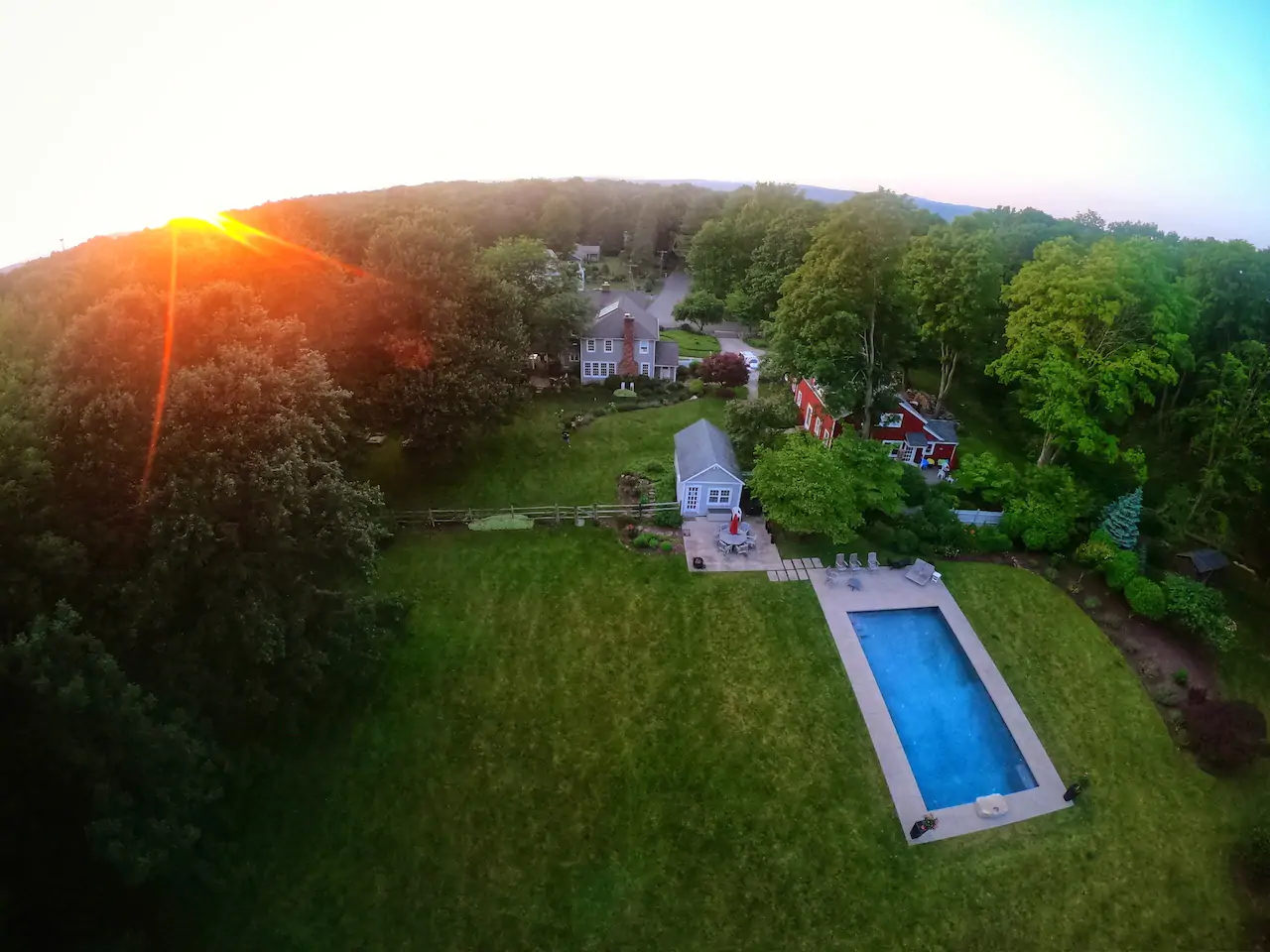 Aerial view of a home on a large plot of a land with a giant pool and lots of green space.