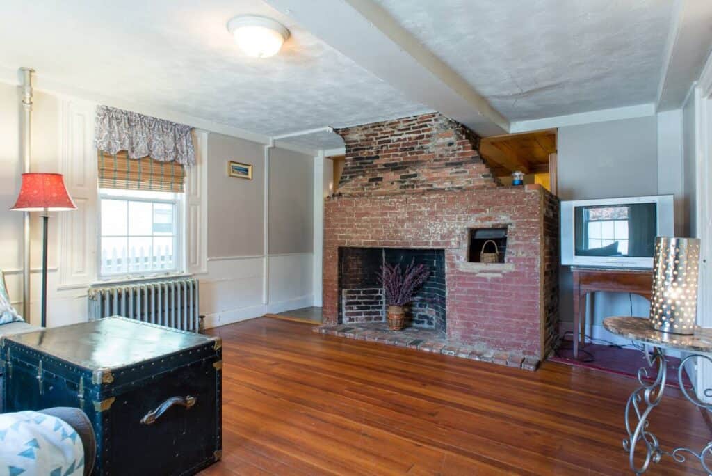 Room with wooden floor, brick fireplace and radiator