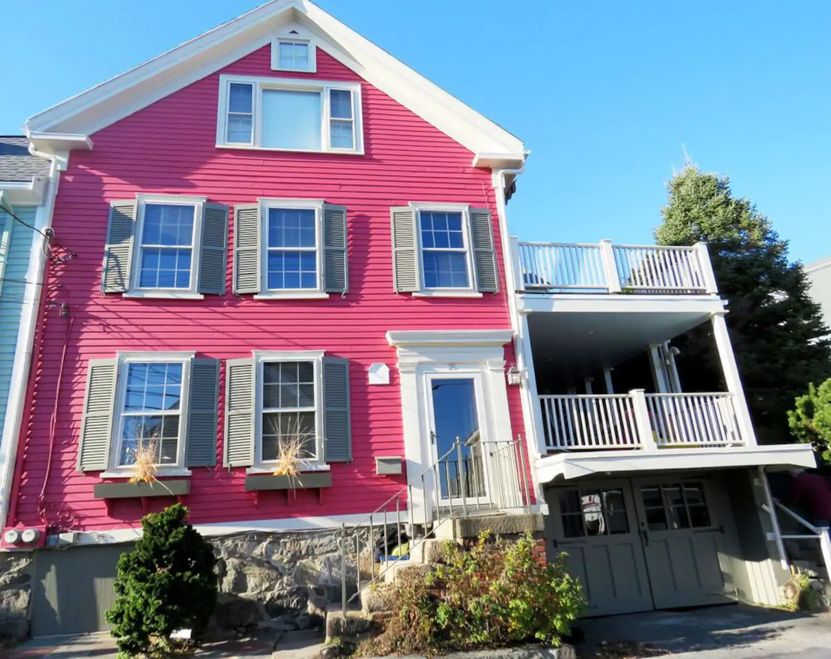 pink new england style house with white balconies to the side