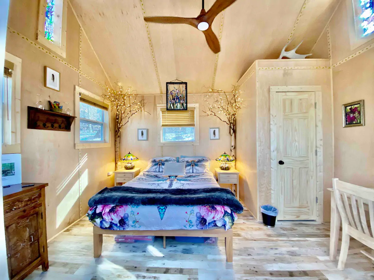A platform bed with blue bedding in a bedroom with a window and a ceiling fan in one of the most popular Airbnbs in Connecticut