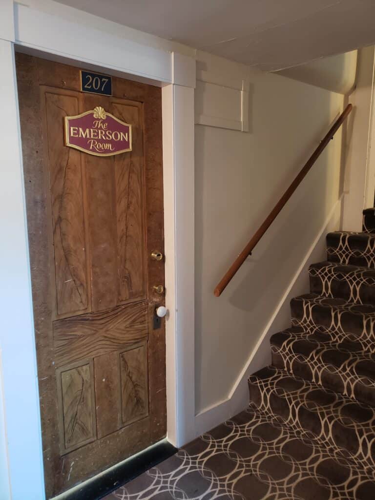 Wooden door that says, \"The Emerson Room\" by steps.