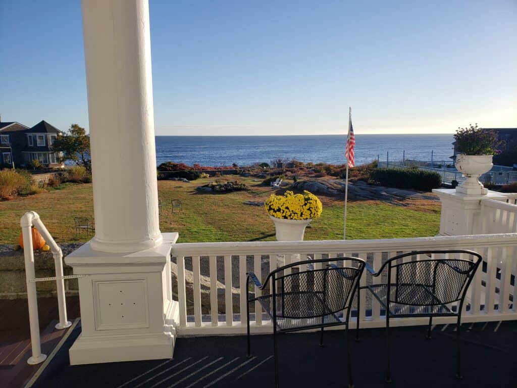 Two chairs on a porch looking out to a view of the ocean.