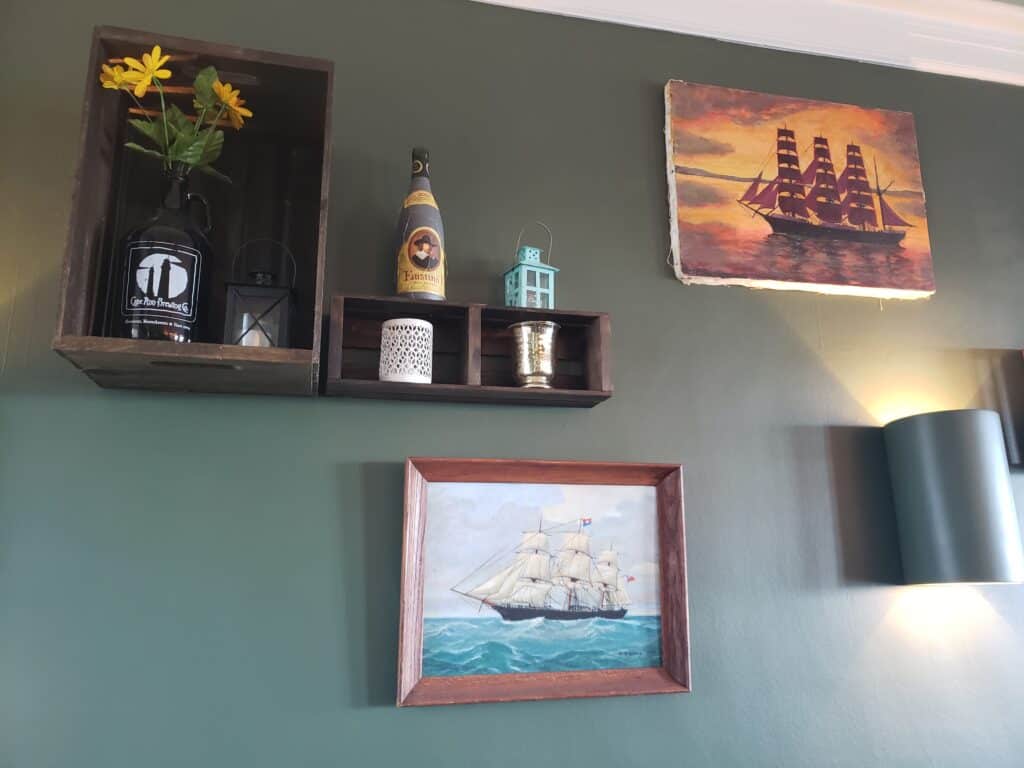 Nautical-themed art pieces hanging on a green wall.