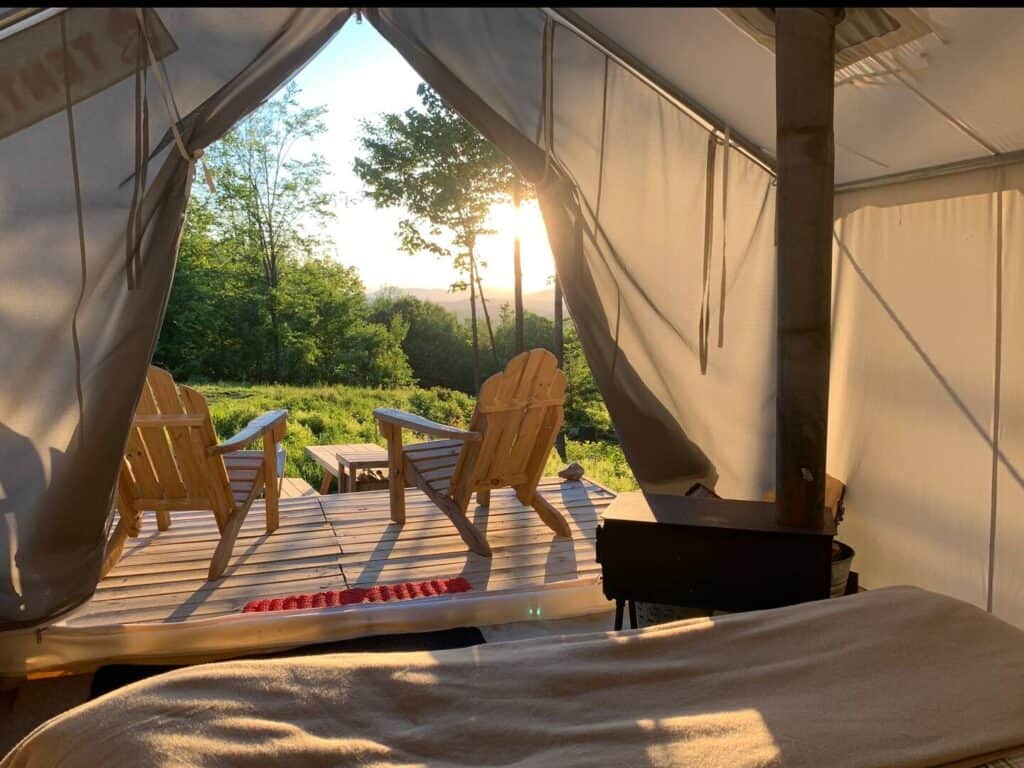 Adirondack chairs in front of a tent in the sun